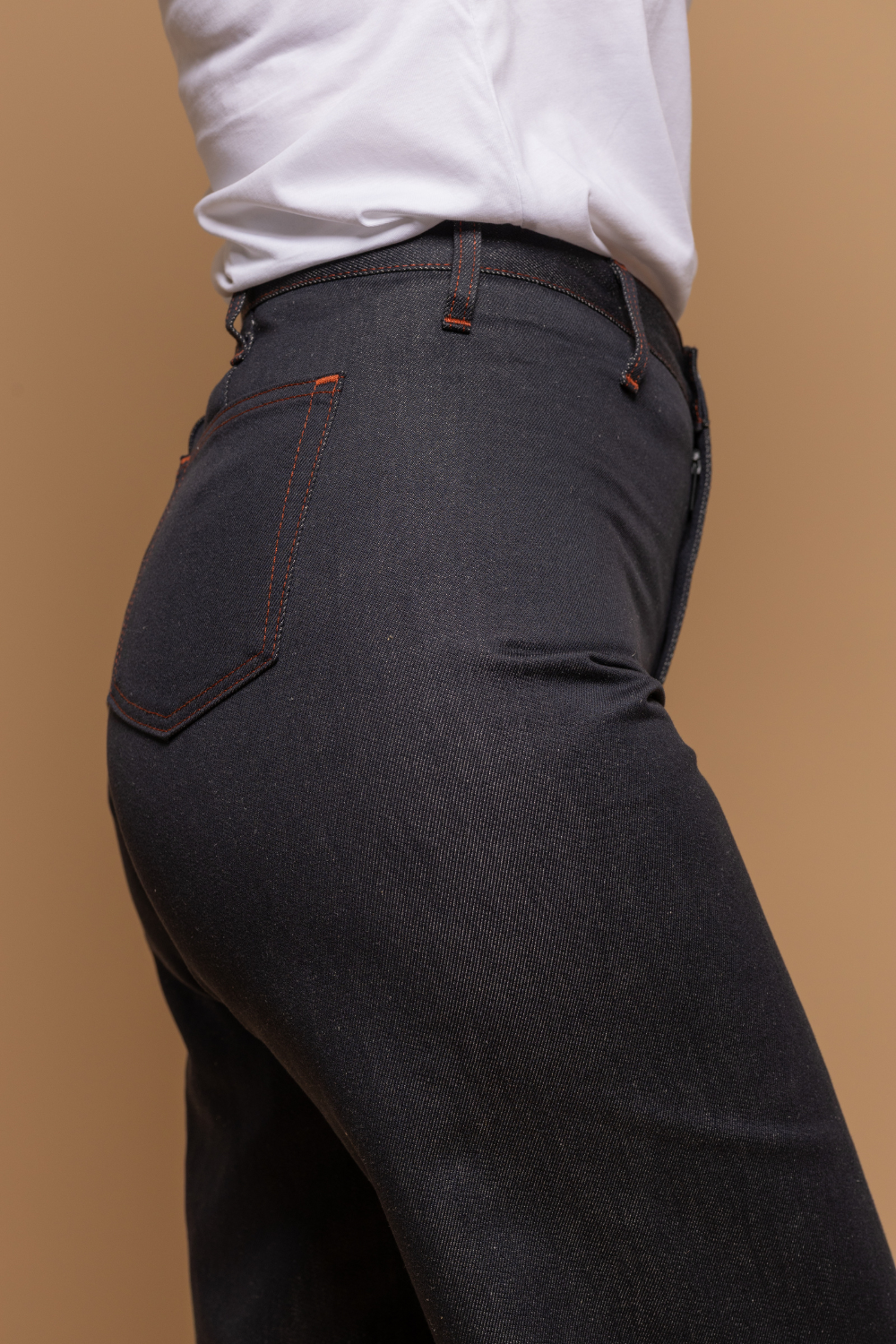 Plan rapproché du jeans en lin et coton bio Flavia à coupe évasée en bas et taille mi-haute, de couleur bleu jeans, détail de la poche arrière, avec un t-shirt blanc, sur fond neutre - Le Gaulois jeans