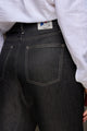 Jeans en lin Lutèce Noir coupe Mom avec une taille haute et une fermeture à glissière, poches arrière visibles et une étiquette Le Gaulois, présenté avec une chemise blanche, sur fond neutre.