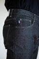 Homme portant le jeans en lin Massalia Noir à coupe droite et taille mi-haute, couleur noire, avec détail de drapeau français sur la poche arrière, tissu robuste en sergé croisé, assemblé en France - Le Gaulois jeans