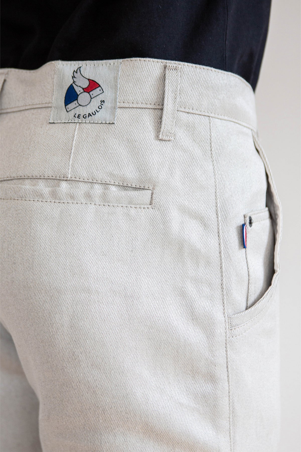 Jeans en lin Lugdunum en Lin Naturel, avec une teinte beige clair ivoire sans teinture, coupe chino ajustée, taille haute, tissé en sergé croisé, fabriqué en France, affichant un écusson Le Gaulois sur la poche arrière droite.
