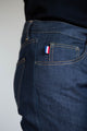 Plan rapproché du jeans en lin Massalia Bleu pour homme, mettant en évidence la poche arrière avec le drapeau français, coupe droite, sur fond uni. Le Gaulois jeans