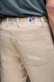 Homme portant le jeans en chanvre L'Aurelien couleur naturelle, coupe droite avec poches italiennes et étiquette Le Gaulois sur fond de t-shirt bleu clair