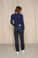 Vue arrière d'une femme portant le jeans en lin Condate Bleu à coupe droite et taille mi-haute, couleur bleu jeans, avec une étiquette indiquant la fabrication française, sur un fond uni beige - Le Gaulois jeans
