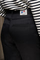 Modèle femme portant le jeans en lin Condate Noir intense avec coupe droite et taille mi-haute, couleur noire intense, associé à un haut à rayures blanches et noires, sur fond neutre - Le Gaulois jeans