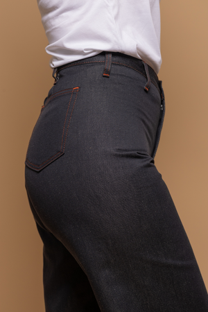 Plan rapproché du jeans en lin et coton bio Flavia à coupe évasée en bas et taille mi-haute, de couleur bleu jeans, détail de la poche arrière, avec un t-shirt blanc, sur fond neutre - Le Gaulois jeans
