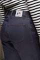 Modèle femme présentant l'arrière du jeans en chanvre et coton bio Isla pour femme avec coupe droite et taille haute, couleur bleu, doté d'un liseré rouge et d'une fermeture à glissière, porté avec un haut à rayures noir et blanc - Le Gaulois jeans