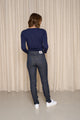 Modèle femme de dos portant le jeans en lin et élasthanne recyclé Nicia bleu avec coupe près du corps et taille haute, couleur bleu jeans, finition sergé croisé, sur fond uni avec étiquette Origine France Garantie visible - Le Gaulois jeans