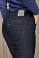 Modèle femme présentant le pantalon Nicia bleu, jeans en lin et élasthanne recyclé, coupe près du corps avec taille haute, fermeture à glissière, sur fond beige, mettant en évidence le tissu sergé croisé et l'étiquette Le Gaulois jeans sur la poche arrière.