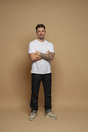 Modèle homme portant le jeans en lin et coton bio Ruscino à coupe droite et taille mi-haute, de couleur bleu jeans, avec un t-shirt blanc et des baskets beiges, sur fond neutre - Le Gaulois jeans