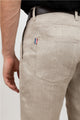 Homme portant L'Aurelien jeans en chanvre naturel, couleur naturelle sans teinture avec coupe droite et poches italiennes devant, montrant le détail de la poche arrière avec un petit drapeau français, fermeture Eclair recyclée et bouton Diabolo en bois de buis, sur fond neutre.