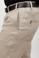 Jeans en chanvre modèle L'Aurelien couleur naturelle avec coupe droite, poches italiennes et fermeture éclair recyclée, présenté avec une ceinture marron sur fond uni