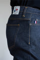Vue latérale d'un homme portant le jeans en lin et élasthanne recyclé modèle Divio bleu, avec une coupe près du corps et taille haute, fermeture à bouton, et détails de coutures jaunes sur tissu bleu jeans, ainsi qu'un écusson Le Gaulois sur la poche arrière - Le Gaulois jeans