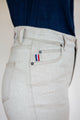 Jeans en lin Condate de couleur naturel ivoire, avec coutures visibles, coupe droite et taille mi-haute, présentant une fermeture à glissière et un écusson tricolore sur la poche, fabriqué en France - Le Gaulois jeans