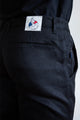 Jeans en lin Lugdunum Noir pour homme avec coupe chino, taille haute et confortable sur les hanches, présentant une fermeture à glissière et une étiquette Le Gaulois à l'arrière, sur fond uni.