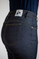 Vue de dos sur le jeans en lin et élasthanne recyclé Nicia bleu pour femme, mis en évidence par la poche arrière avec coutures jaunes et l'étiquette Le Gaulois jeans, mettant en avant la coupe près du corps et la taille haute.