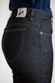 Vue de dos d'une femme portant le jeans en lin et élasthanne recyclé modèle Nicia Noir à coupe près du corps et taille haute, de couleur noire avec surpiqûres contrastantes et étiquette avec logo sur la poche arrière, sur un fond neutre.