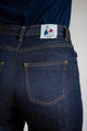 Jeans en lin pour femme Condate Bleu avec coupe droite et taille mi-haute, présentant un tissu sergé croisé en 100% Lin de Normandie, couleur Bleu jeans avec une étiquette Le Gaulois sur la ceinture arrière, sur fond uni.
