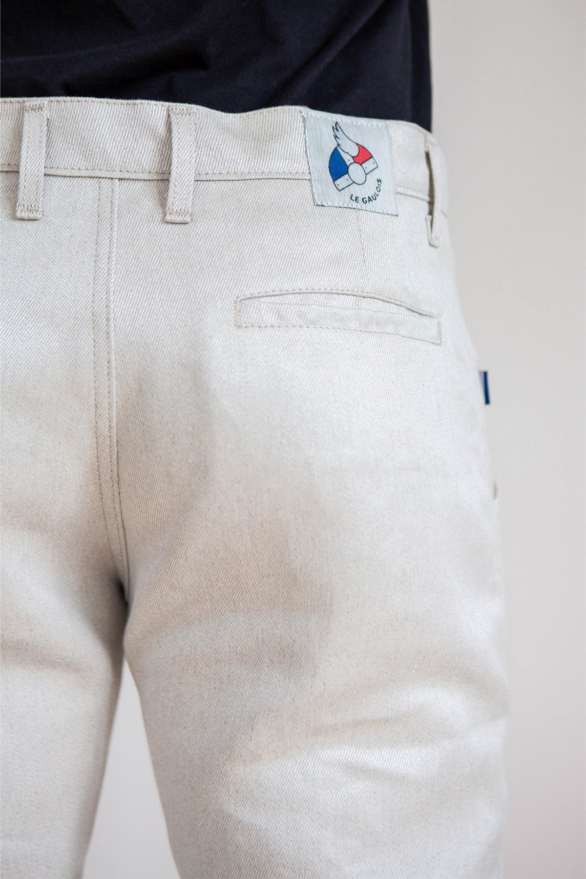 Jeans en lin modèle Lugdunum en lin naturel avec couleur beige clair ivoire, coupe chino confortable aux hanches et effilée aux chevilles, taille haute et fermeture à glissière, fabriqué en France, présenté sur fond neutre.
